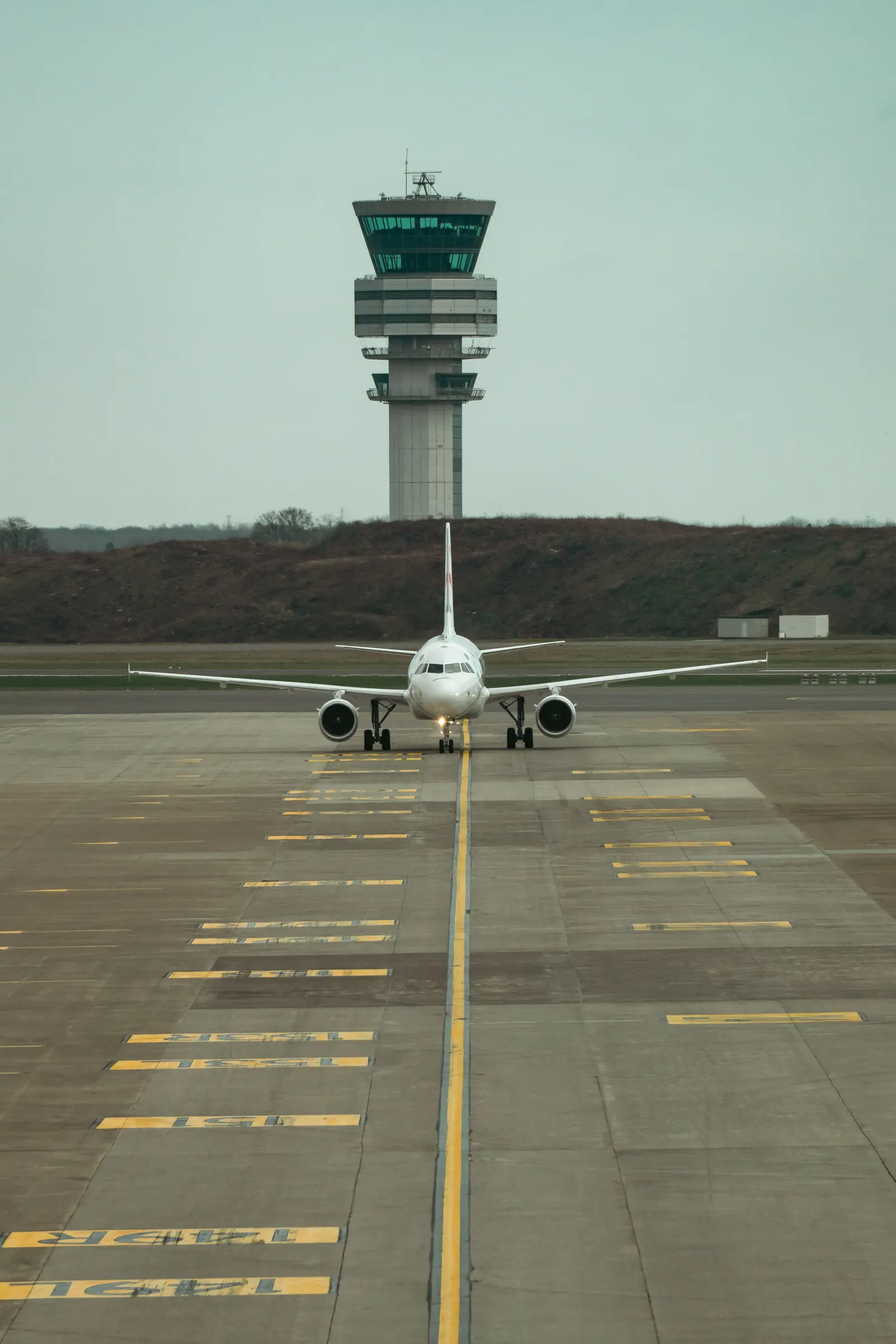 An airliner lined up on a runway, with a control tower behind it at Brussels Airport.